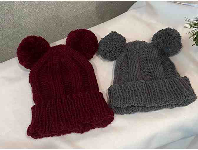 Two knitted hats with pom poms