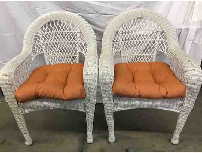 3 white wicker chairs with orange cushions