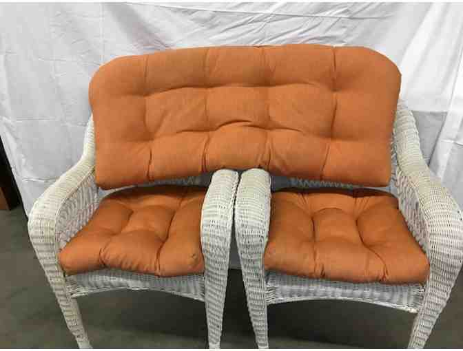 3 white wicker chairs with orange cushions