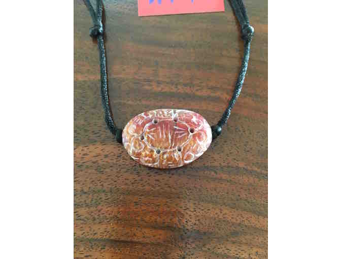 Double-sided carved serpentine amulet necklace.